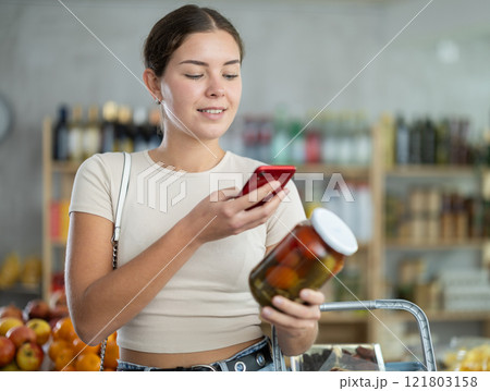 Young woman scanning qr code of pickled tomatoes with cucumbers 121803158