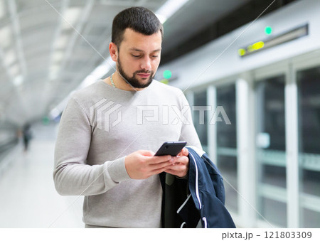 Guy traveler standing on subway station with phone in hands Guy traveler standing on subway station with phone in hands 121803309