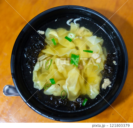 Wonton soup is cooked dumplings filled with meat or seafood. They are served in broth, usually enriched with onions and other ingredients. Chinese cuisine Wonton soup is cooked dumplings filled with meat or seafood. They are served in broth, usually enriched with onions and other ingredients. Chinese cuisine 121803379