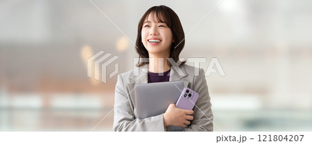 パソコンとスマホを持つ笑顔の女性・ビジネスウーマン 121804207