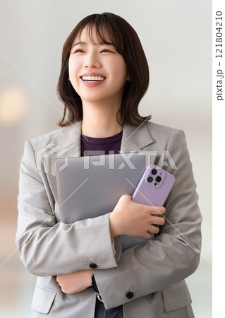 パソコンとスマホを持つ笑顔の女性・ビジネスウーマン パソコンとスマホを持つ笑顔の女性・ビジネスウーマン 121804210