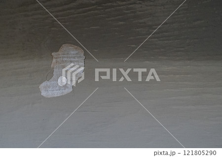 Wood paint peeling off a grey wall with a small hole in it Wood paint peeling off a grey wall with a small hole in it 121805290
