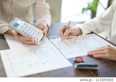 不動産の契約を結ぶ女性2人の手元 121805868