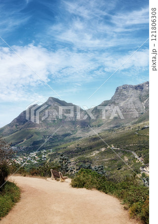 Sandy path through a landscape with mountains against a cloudy blue sky background with copy space. Peaceful and scenic view of a rugged hiking trail to explore on a walk while in nature outdoors Sandy path through a landscape with mountains against a cloudy blue sky background with copy space. Peaceful and scenic view of a rugged hiking trail to explore on a walk while in nature outdoors 121806308