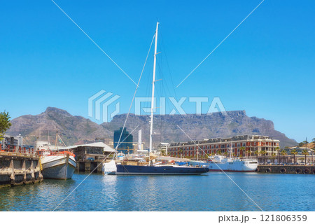 Sailboats docked at a harbor with Table Mountain in the background against blue sky with copy space. Scenic landscape of waterfront port at a marina dockyard. Nautical vessels for travel and tourism Sailboats docked at a harbor with Table Mountain in the background against blue sky with copy space. Scenic landscape of waterfront port at a marina dockyard. Nautical vessels for travel and tourism 121806359