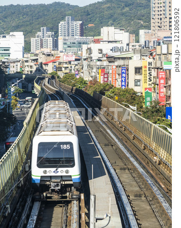 View of a Wenhu or Brown line train running on the elevated track of the Taipei Mass Rapid Transit System with the building background. View of a Wenhu or Brown line train running on the elevated track of the Taipei Mass Rapid Transit System with the building background. 121806592