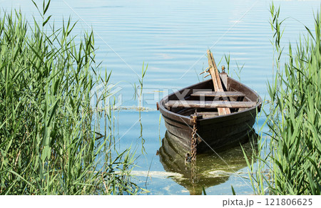 an old wooden boat with oars stands in a small bay on the lake 121806625