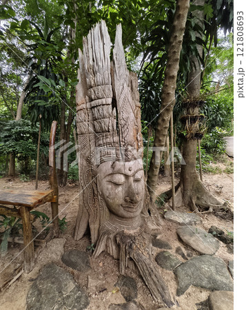 A stunning and beautiful tree sculpture showcasing a serene face A stunning and beautiful tree sculpture showcasing a serene face 121808693