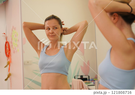 Young woman in a modern bathroom washing her face and brushing her teeth  121808716