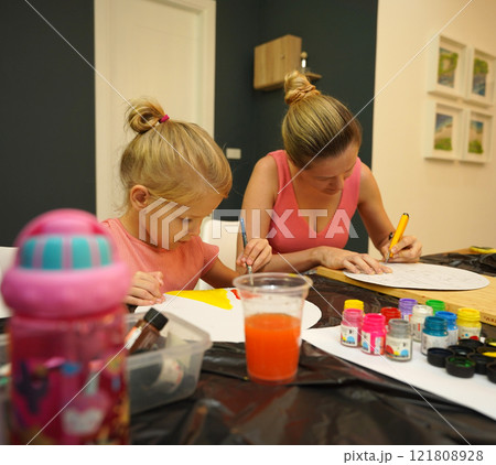 A mother and her young daughter engage in a colorful painting activity  121808928