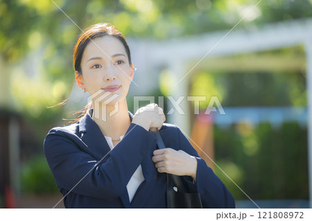 歩道を歩くスーツの女性 121808972