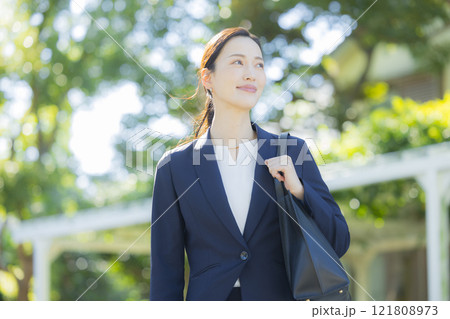 歩道を歩くスーツの女性 121808973