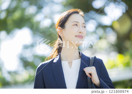 歩道を歩くスーツの女性 121808974