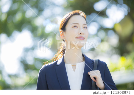 歩道を歩くスーツの女性 121808975