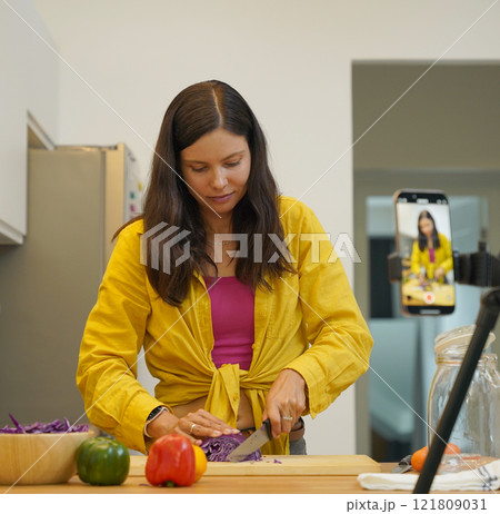 Young woman is broadcasting live from workshop how to prepare a vegetarian food Young woman is broadcasting live from workshop how to prepare a vegetarian food 121809031