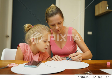 A mother and her young daughter engage in a colorful painting activity A mother and her young daughter engage in a colorful painting activity 121809037