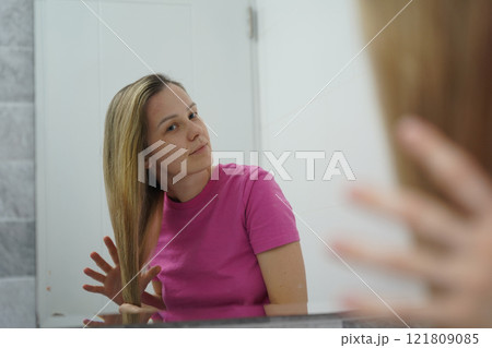 A woman is expertly styling her hair using a blow dryer and brush while in the bathroom 121809085