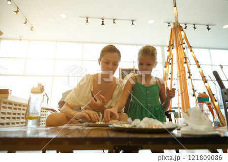 Mother and her daughter paint Halloween cookies  121809086