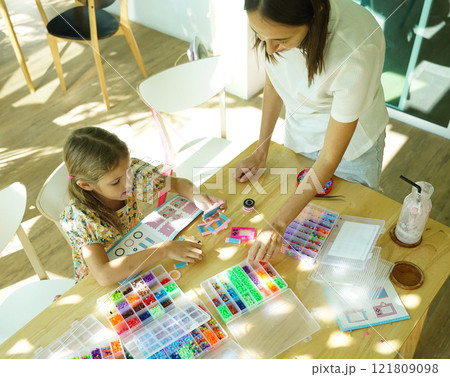 Teacher in workshop teched two girls how to assemble a thermo mosaic  121809098