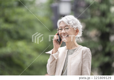 スマートフォンで通話する笑顔のシニア女性 スマートフォンで通話する笑顔のシニア女性 121809129