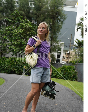 A woman is rollerblading gracefully on a road located in a park A woman is rollerblading gracefully on a road located in a park 121809220