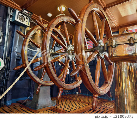 A row of wooden steering wheels located on an old vessel A row of wooden steering wheels located on an old vessel 121809373