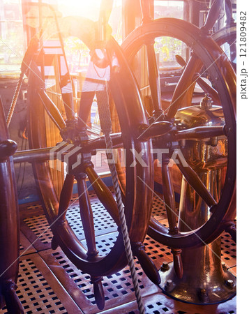 A row of wooden steering wheels located on an old vessel A row of wooden steering wheels located on an old vessel 121809482