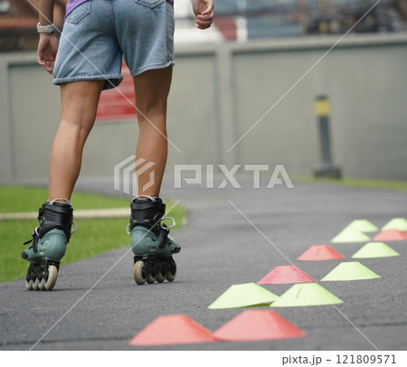 A woman is rollerblading gracefully on a road located in a park A woman is rollerblading gracefully on a road located in a park 121809571