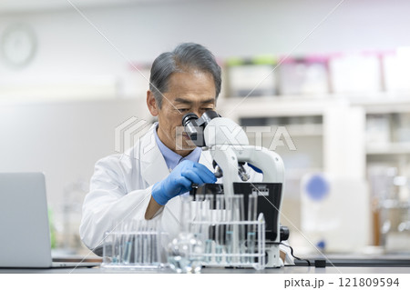 顕微鏡で作業をする白衣を着た男性　実験・研究・開発イメージ 121809594