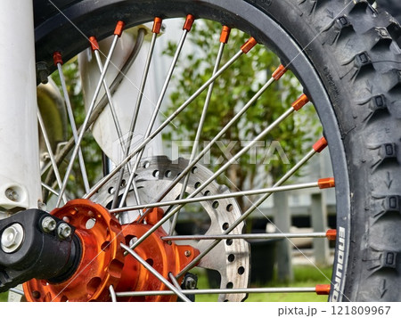 Closeup view of a motorcycle wheel on a grassy field Closeup view of a motorcycle wheel on a grassy field 121809967