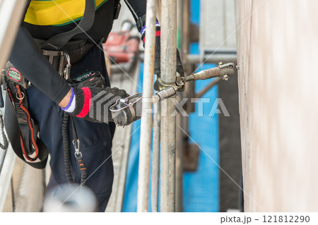 【マンション大規模修繕工事　壁つなぎを接続し足場を作る作業員】 121812290