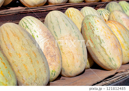 Vibrant display of fresh melons at a bustling local market in summer sun 121812485