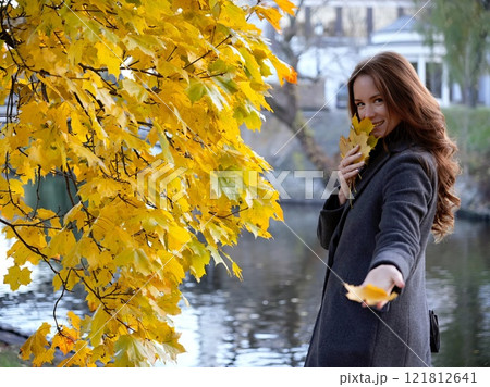 Girl, autumn image near yellow leaves in gray coat. Riga, Latvia 121812641