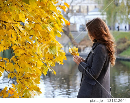 Girl, autumn image near yellow leaves in gray coat. Riga, Latvia 121812644