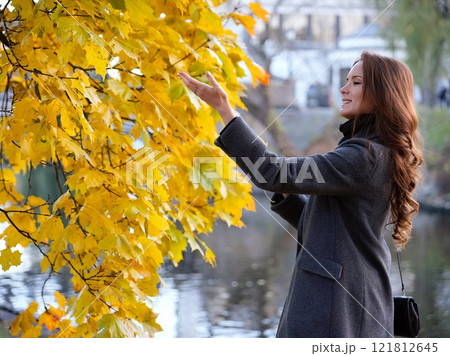 Girl, autumn image near yellow leaves in gray coat. Riga, Latvia 121812645