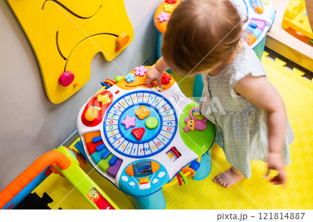 Child interacting with educational toy table in vibrant space. Concept of joyful learning and creativity Child interacting with educational toy table in vibrant space. Concept of joyful learning and creativity 121814887