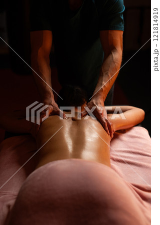Massage of a woman's back in a spa salon. Male masseur. 121814919