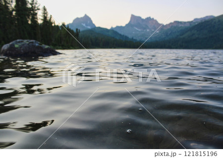Rippling water in mountain lake. Twilight, shore of pond, Summer landscape Rippling water in mountain lake. Twilight, shore of pond, Summer landscape 121815196