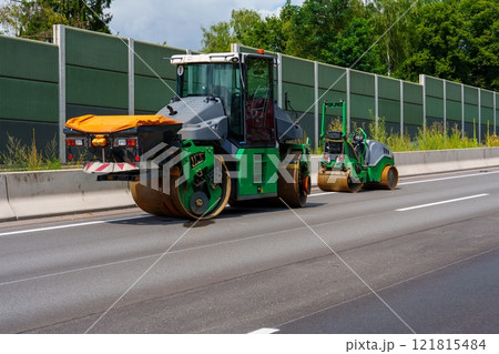 Two Green Road Construction Vehicles Paving New Asphalt on a Highway 121815484