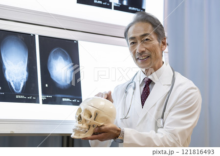 頭蓋骨の模型を持って説明する男性医師 頭蓋骨の模型を持って説明する男性医師 121816493