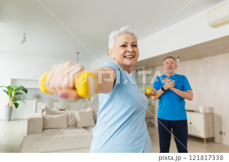 Fitness workout training. Senior woman picking up dumbbells. Old adult mature healthy lady doing sports exercise at home. Grandmother have workout rehabilitation. Health care healthy lifestyle Fitness workout training. Senior woman picking up dumbbells. Old adult mature healthy lady doing sports exercise at home. Grandmother have workout rehabilitation. Health care healthy lifestyle 121817338