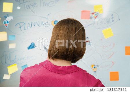 Beautiful businesswoman putting sticker on glass board. Back view. Immaculate. Beautiful businesswoman putting sticker on glass board. Back view. Immaculate. 121817531