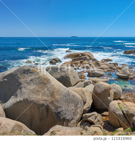 Beautiful seascape beach waves splashing against boulders or big stones in aqua sea water. A summer nature location in South Africa. Rocks in the ocean under a blue sky background with copy space. Beautiful seascape beach waves splashing against boulders or big stones in aqua sea water. A summer nature location in South Africa. Rocks in the ocean under a blue sky background with copy space. 121818960