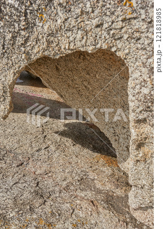 Closeup of rough rock with deep cracks, holes and crevices from wind, heat or water erosion from global warming or climate change. Texture detail and background of sedimentary rock or granite outside 121818985