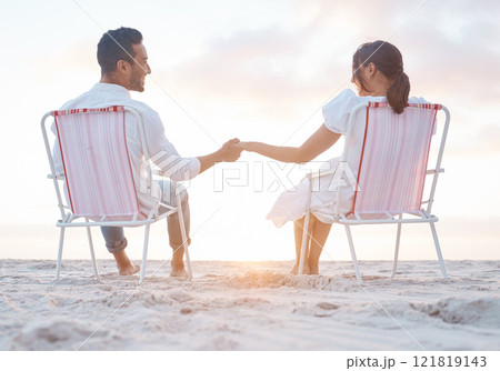 Couple, beach chair and holding hands on holiday, care and outdoor at sunset, back and bonding in summer. People, man and woman with love, smile and relax together on vacation by ocean in Indonesia 121819143