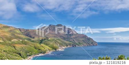 A landscape of a mountainside with an ocean view and blue sky background with a lush, green botanical garden or national park. A scenic environment with rocky and rough terrain in a remote location 121819216