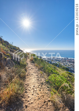 Hiking trail on Table Mountain with a clear blue sky, cityscape and sea with copyspace. Beautiful landscape of dirt road leading through lush wild bushes and plants. Discover the wonders of Cape town 121819218