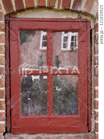Closeup of an old dirty window in a red brick home. Zoom in on casement with red wood frame on a historic building with bumpy paint texture. Macro exterior details of windowsill in a traditional town Closeup of an old dirty window in a red brick home. Zoom in on casement with red wood frame on a historic building with bumpy paint texture. Macro exterior details of windowsill in a traditional town 121819525