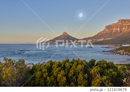 Lush plants in nature with the ocean and mountain in background against blue sky with a full moon. Scenic popular natural landmark and tourist attraction for adventure while on vacation in Cape Town 121819679