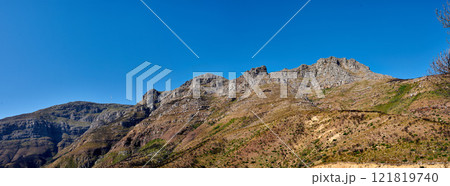 Twelve Apostles at Table Mountain in Cape Town against a blue sky background from below. Breathtaking view of plants and shrubs growing around a majestic rocky valley and scenic landmark in nature Twelve Apostles at Table Mountain in Cape Town against a blue sky background from below. Breathtaking view of plants and shrubs growing around a majestic rocky valley and scenic landmark in nature 121819740